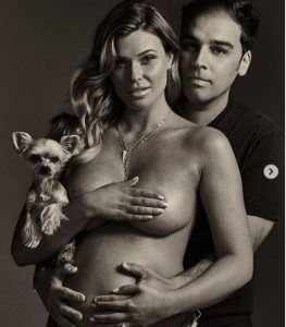 Samantha Hoopes with her partner behind holding her baby bump