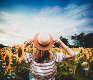 a wom,an holding her hat in a sunflower farm