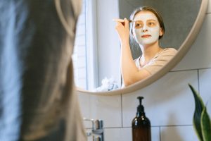 a reflection of a woman in mirror with face pack